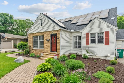 Front view of a house with garden, stone steps, and solar panels on the roof.