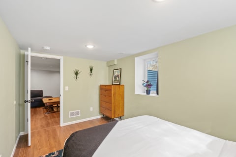 Modern bedroom with a bed, wooden dresser, and wall planters.