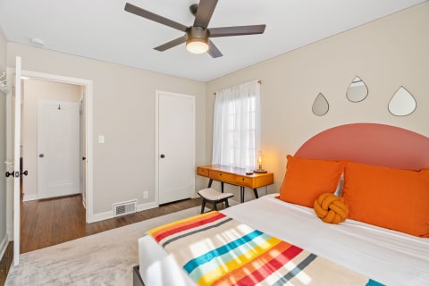 A cozy bedroom with colorful bedding, a modern ceiling fan, and elegant decor.
