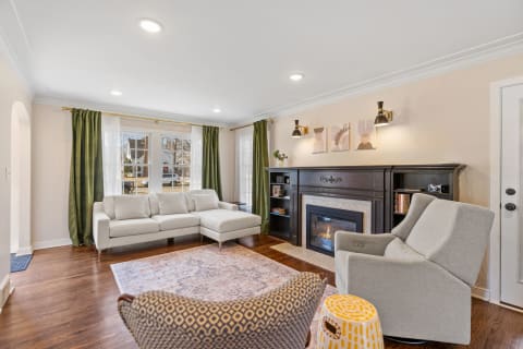 Cozy living room with gray sectional sofa, green curtains, and a fireplace.
