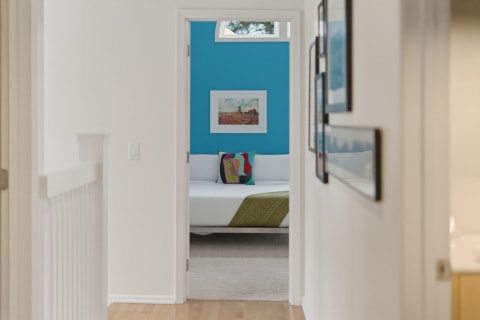 Narrow hallway leading to a colorful bedroom with turquoise walls and decorative elements.