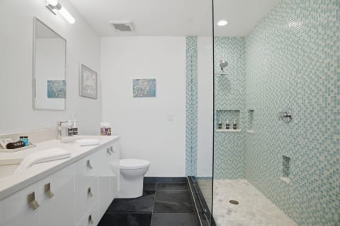 Modern bathroom with mosaic tiles and walk-in shower, showcasing elegant finishes.