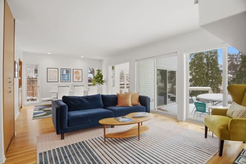 Modern living room with navy sofa, coffee table, and access to balcony.