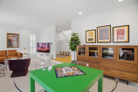 Modern living room with a green game table, leather sofa, and decorative artwork.