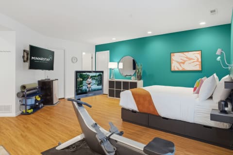 Modern bedroom featuring a teal accent wall, fitness equipment, and contemporary decor.