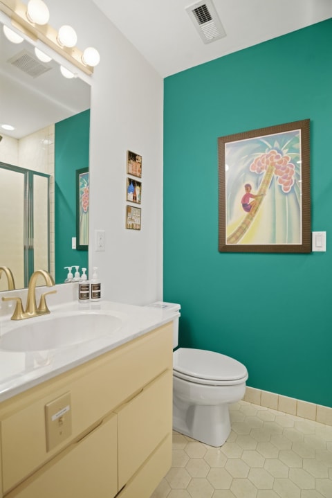 A stylish bathroom featuring a teal wall and a modern sink with beige cabinetry.