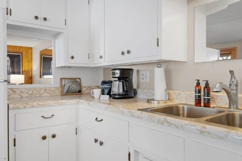 A kitchen corner featuring a coffee maker, white cabinets, and a marble countertop.