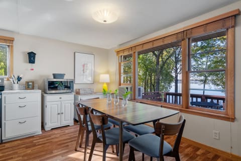 Cozy dining area with wooden table and views of trees and water.