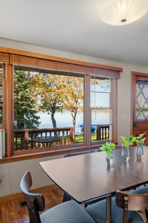 Dining room with a view of trees and a lake through a window.