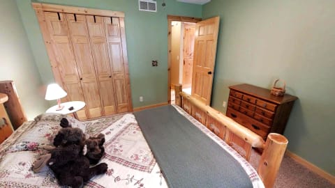 A warm rustic bedroom with a log bed, stuffed animals, and wooden furniture.
