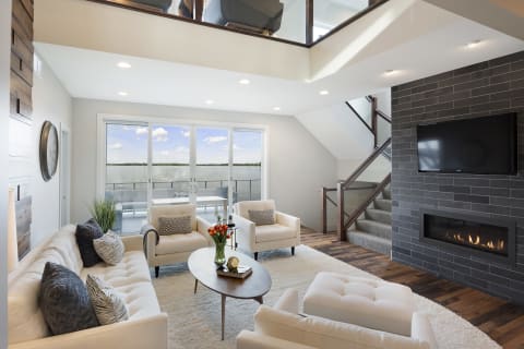 Contemporary living room featuring a cozy sofa, chairs, and large windows overlooking water.