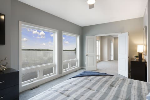 Bright and airy bedroom showcasing large windows with a lake view.
