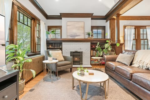 Inviting living room with brown leather sofa, accent chair, and decorative plants.