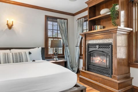 Stylish bedroom featuring a plush bed, decorative throw pillow, and a fireplace.