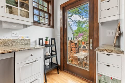 A modern kitchen with granite countertops and a view of the backyard through a glass door.