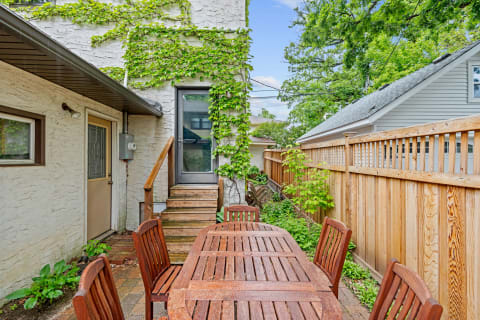 Outdoor dining area featuring a wooden table and lush ivy on the wall.