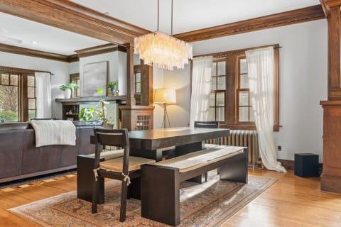 Dining area with dark wood table, woven seat cushions, and an elegant chandelier.