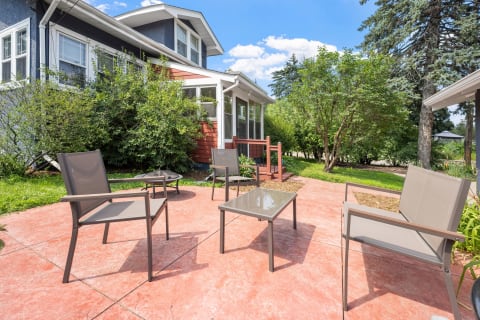 Outdoor seating area with chairs and tables surrounded by greenery.