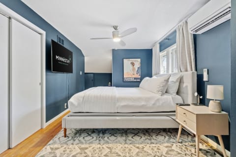 Cozy bedroom with navy blue walls, modern bed, and vintage movie poster.