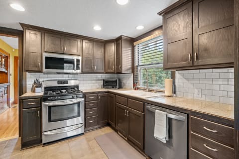 Contemporary kitchen with dark cabinetry, stainless steel appliances, and a natural light-filled window.