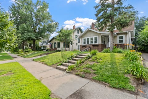 Suburban neighborhood with charming houses and vibrant gardens along a sidewalk.