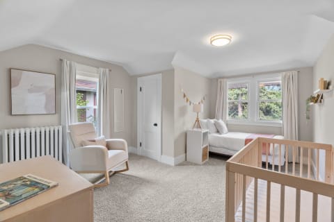 Cosy nursery featuring a crib, rocking chair, and natural light from windows.