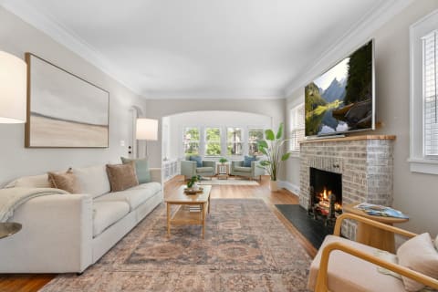 Cozy living room featuring a beige sofa, a fireplace, and large windows.