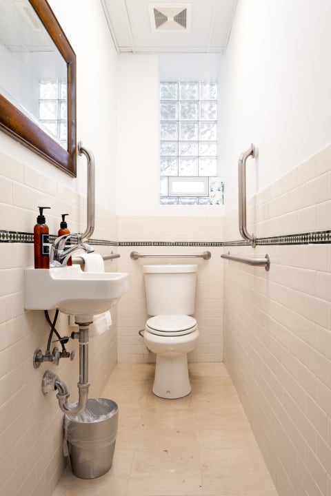 Interior view of a modern restroom featuring a sink and toilet, with light tile and natural light.