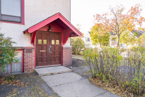 Entrance of a building featuring wooden double doors under a red overhang.