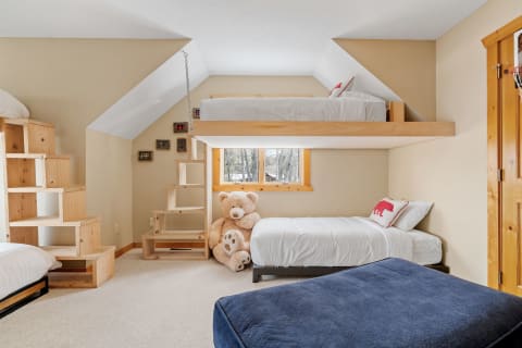 Cozy children's bedroom featuring a wooden bunk bed, teddy bear, and natural light.
