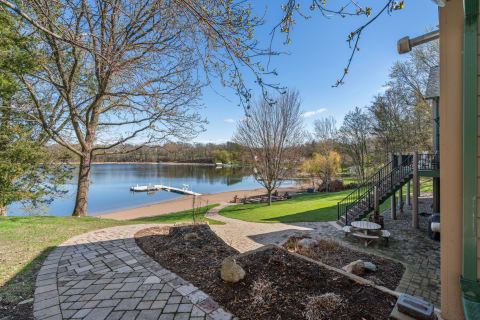 Scenic view of a lake with a pathway, trees, and a dock on a sunny day.