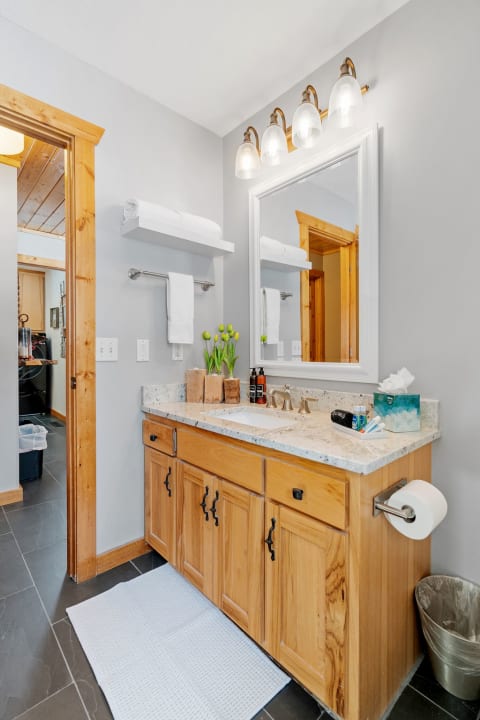Interior view of a contemporary bathroom with wooden vanity, mirror, and decorative elements.