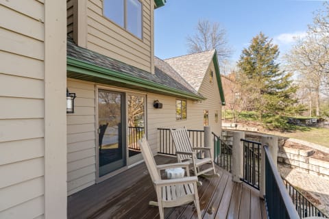 Wooden deck with rocking chairs and lush greenery in the background.