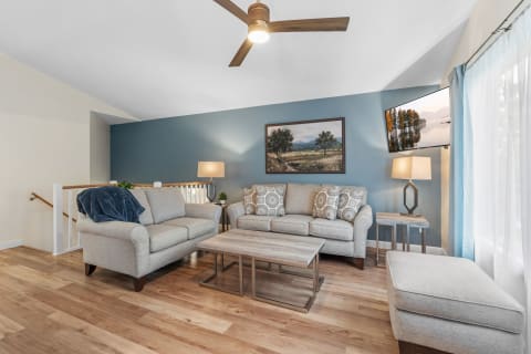 A modern living room featuring gray sofas, a coffee table, and a blue accent wall.