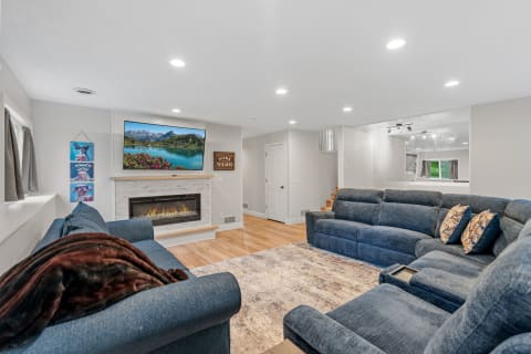 A modern living room featuring a blue sectional sofa, fireplace, and mounted TV.
