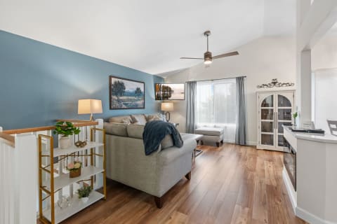 Living room with blue walls, gray sectional sofa, and natural light from large windows.