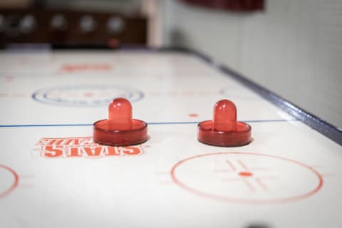 Two red pucks on an air hockey table, featuring distinctive markings.