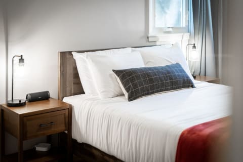 A neatly arranged bed in a modern bedroom with a nightstand and lamp.