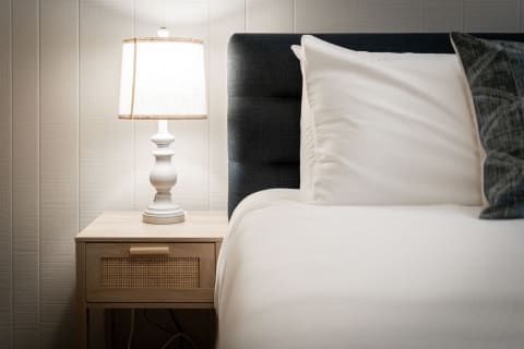 Cozy bedroom corner with a bed, nightstand, and lamp.