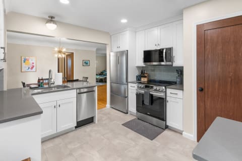Contemporary kitchen featuring white cabinetry and stainless steel appliances.