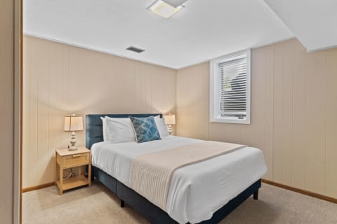 Cozy bedroom featuring a double bed with white linens and a decorative blue pillow.