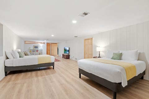 A bright and spacious bedroom featuring two large beds, wooden flooring, and modern furnishings.