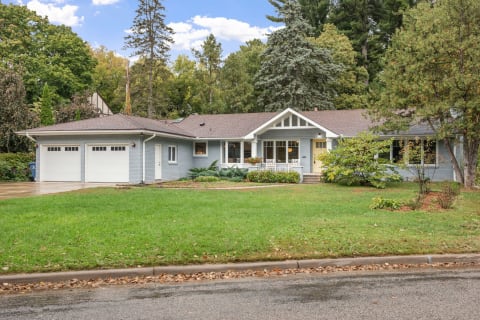 A blue-gray single-story house with a neat lawn and a double garage.