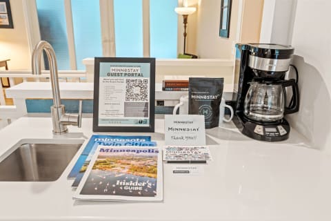 Kitchen countertop with faucet, coffee maker, MINNESTAY guest information, and brochures.