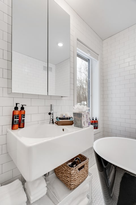 A contemporary bathroom featuring a white sink, black bathtub, and decorative elements.