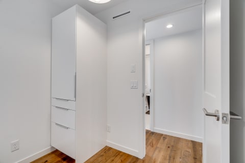Interior view of a hallway with a white cabinet and door leading to a bathroom.