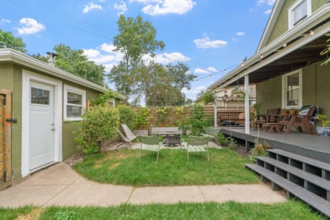 A backyard with a fire pit surrounded by chairs and a wooden deck.
