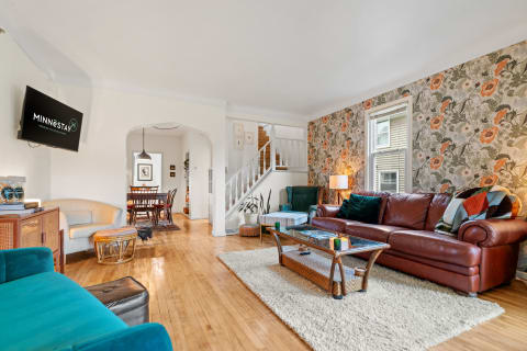 Warm living room with floral wallpaper and mixed seating arrangements.
