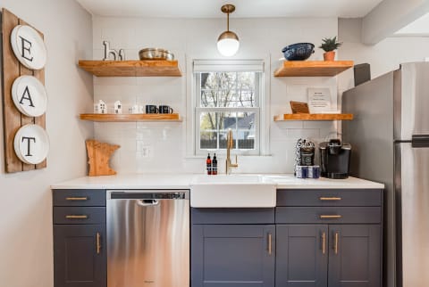Modern kitchen with a farmhouse sink, gray cabinets, and stylish decor.