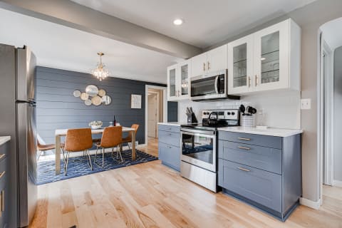 Modern kitchen with navy cabinets, stainless steel appliances, and a dining area.